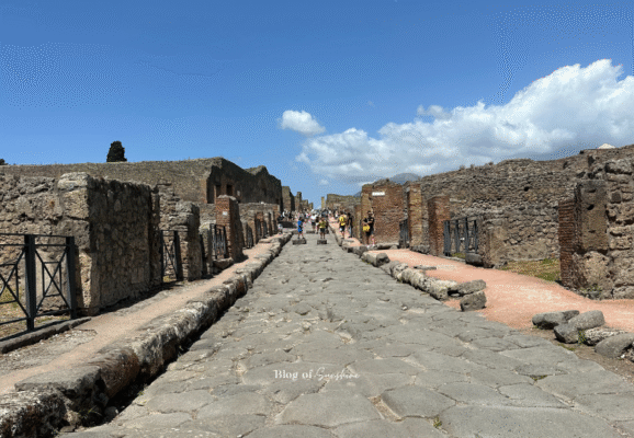 Original Roman road in Pompeii with ruins of houses and shops on both sides