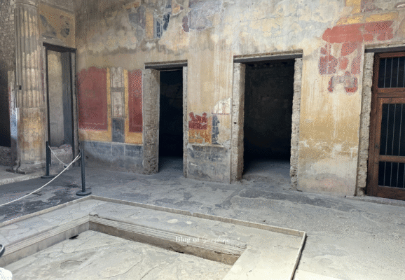View of the atrium in the House of the Vettii, Pompeii, showing an impluvium, frescoed walls, and multiple doorways