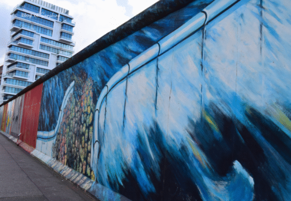 Painting of a crowd behind a barrier on the Berlin Wall, symbolic of division