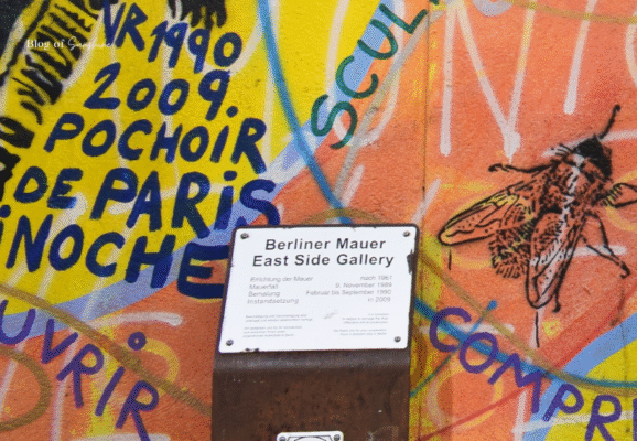 Informational sign at the East Side Gallery on a colorful graffiti background