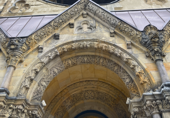 Close-up of the ornate arched entrance to Kaiser Wilhelm Memorial Church in Berlin, showcasing detailed stone carvings