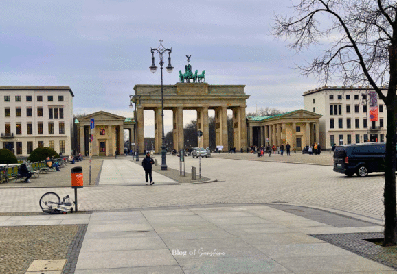 Distant view of the Brandenburg Gate in Berlin with people walking along Unter den Linden toward the monument