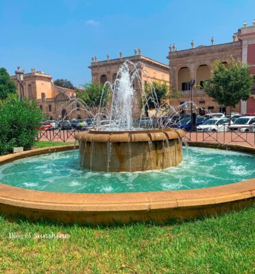 Decorative fountain in Plaça des Born with Ciutadella’s City Hall and historic buildings in the background on a sunny day
