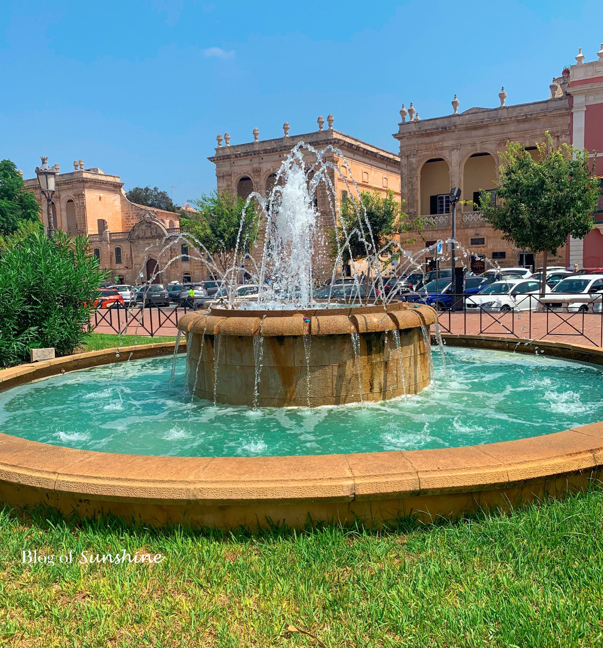Decorative fountain in Plaça des Born with Ciutadella’s City Hall and historic buildings in the background on a sunny day