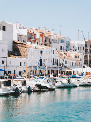 Waterfront buildings and moored sailboats at the harbor in Ciutadella, Menorca on a sunny day