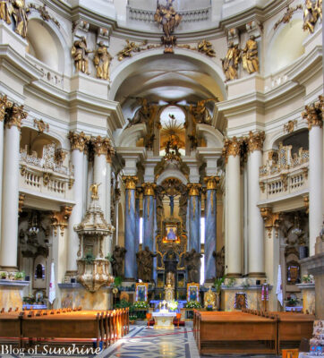 Lavish Baroque interior of the Dominican Church in Lviv, featuring a grand altar, gold detailing, and soaring columns