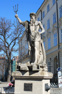 The Fountain of Neptune statue holding a trident in Rynok Square, Lviv, one of four mythological sculptures on each corner of the square