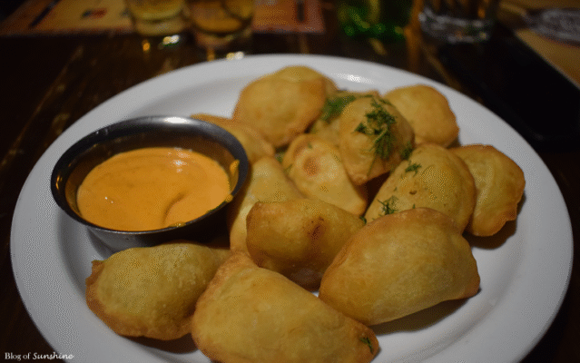 Plate of golden fried Ukrainian varenyky dumplings served with dipping sauce at a restaurant in Lviv