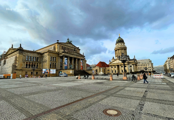 Wide view of Gendarmenmarkt in Berlin featuring the Konzerthaus and Französischer Dom under dramatic skies