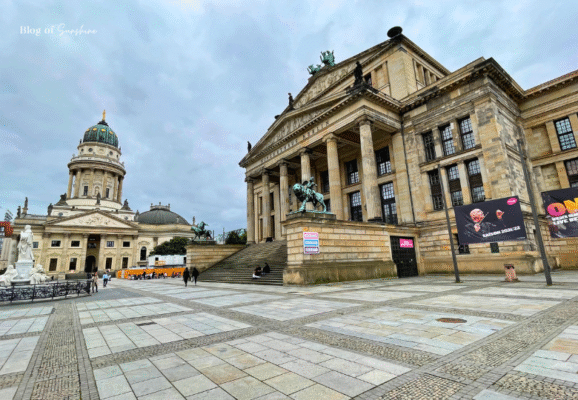 A wide view of Gendarmenmarkt square in Berlin showing the Konzerthaus Berlin and the French Cathedral on a cloudy day