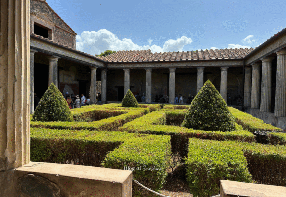 Peristyle garden in the House of the Vettii, Pompeii, with trimmed box hedges and a columned portico