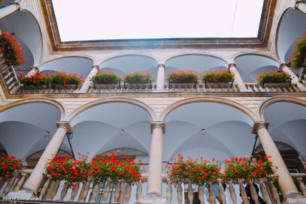 Upward view of the arched balconies and red flower boxes in the Italian Courtyard of Kornyakt Palace, Lviv