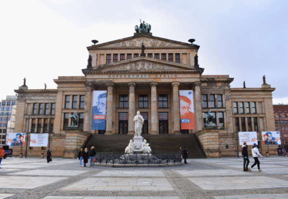 The grand front façade of the Konzerthaus Berlin with a central statue at Gendarmenmarkt square.