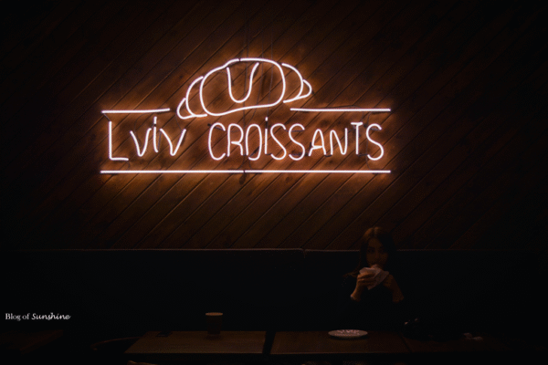 Neon sign of Lviv Croissants cafe glowing on wooden wall in Lviv, Ukraine