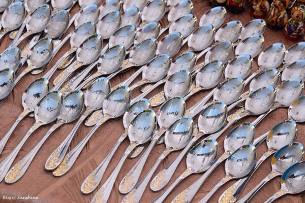 Rows of shiny souvenir spoons with Lviv engravings displayed at a market stall in Lviv, Ukraine