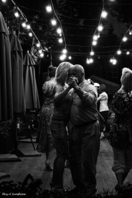 Black-and-white photo of a couple slow dancing under glowing lights at an evening event in Lviv, Ukraine