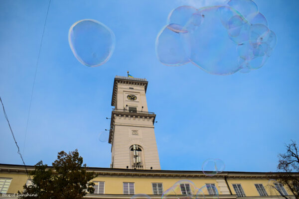 Lviv Town Hall tower on a bright day with floating bubbles under a blue sky