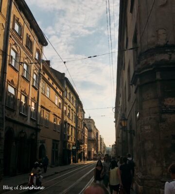 People walking along a tram-lined street in Lviv, Ukraine during golden hour with historic architecture on both sides