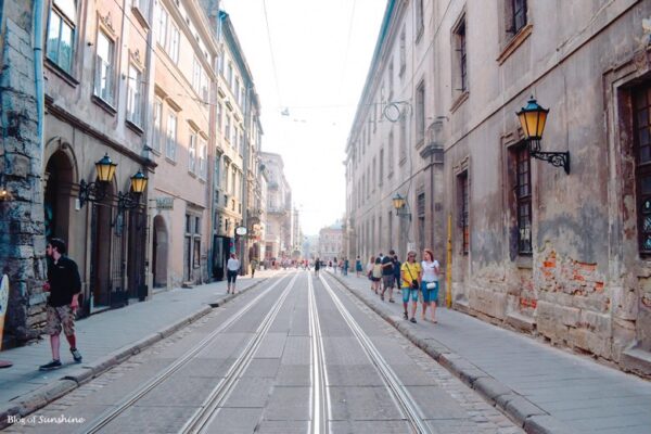 Tram tracks running through a scenic pedestrian street in Lviv Old Town with people strolling and vintage buildings