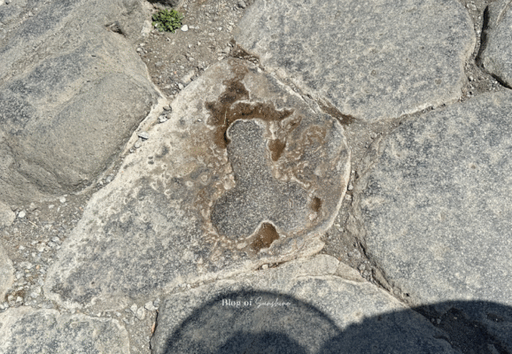 Phallic carving on a stone road in Pompeii, symbolizing protection and possibly pointing to a brothel