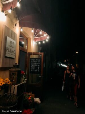 Piano flower shop and café in Lviv illuminated by warm string lights at night, with flower baskets and coffee menu board