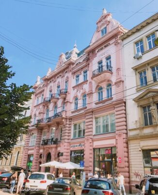 Beautiful pink historic building with ornate balconies on a lively street in Lviv, Ukraine