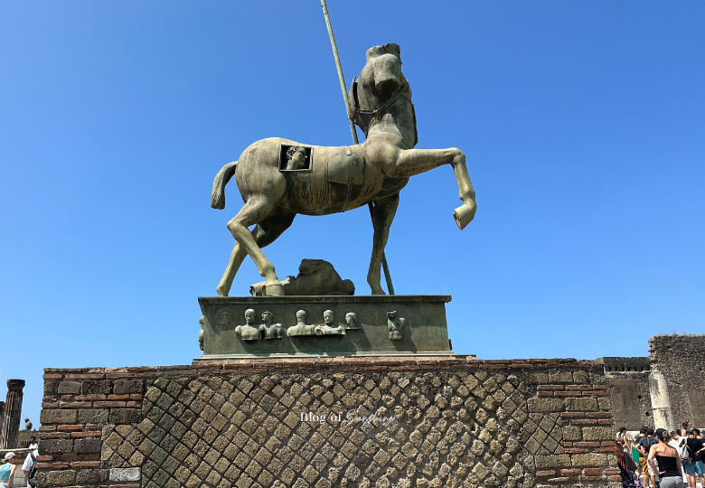 Bronze centaur statue by Igor Mitoraj standing in the Forum of Pompeii under a clear blue sky