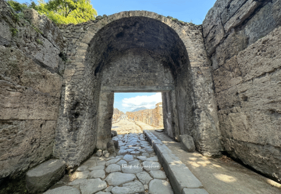 Ancient Roman road in Pompeii leading under a stone archway