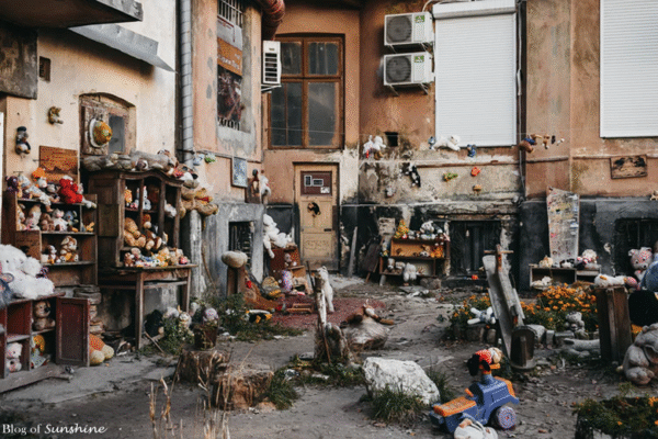 Eerie scene of the Yard of Lost Toys in Lviv showing worn stuffed animals and scattered dolls in a crumbling courtyard