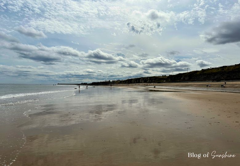 Seaham Hall Beach with wide sandy shoreline, cliffs and people walking along the Durham Coast