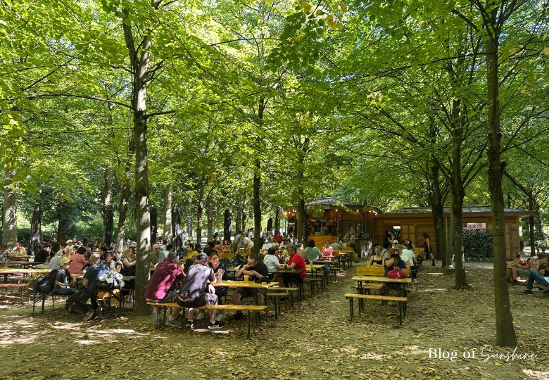 Tree‑lined walkway in Brussels Park with café visible under shade
