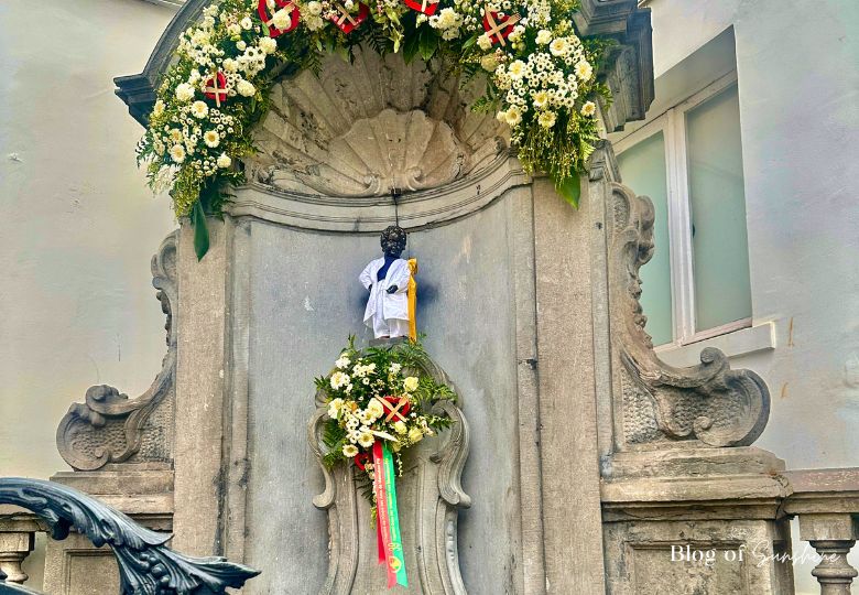 Manneken Pis statue in Brussels dressed in ceremonial outfit with flower wreaths