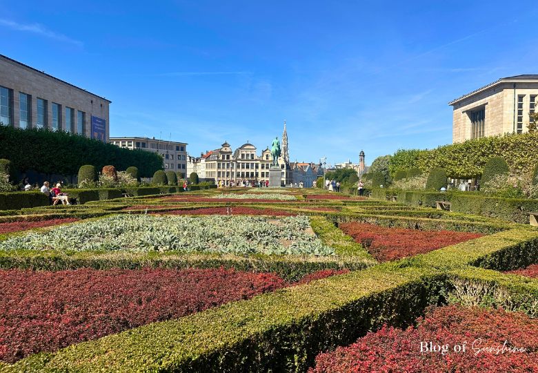 View over Mont des Arts gardens toward statue and old town rooftops.
