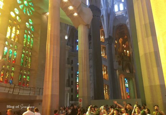Visitors inside the Sagrada Família surrounded by warm stained-glass reflections