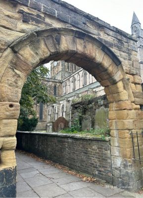 Stone archway leading into the churchyard with Hexham Abbey in the background