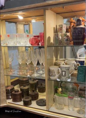 Glass cabinet in a Hexham antique shop filled with vintage glassware, mugs and ornaments