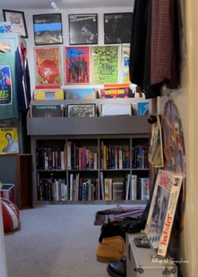 Wall of album covers and racks of vinyl records with shelves of second-hand books in a Hexham shop