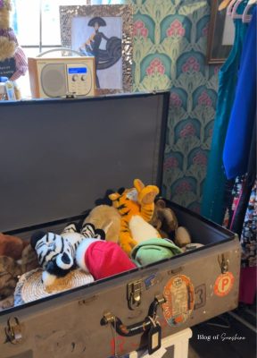 Open trunk filled with soft toys and dressing-up hats inside a quirky Hexham vintage shop