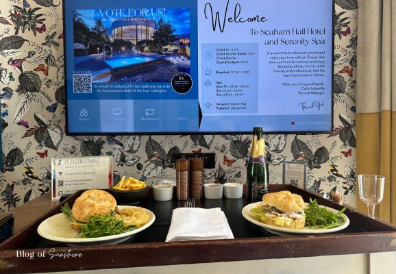 Room service at Seaham Hall Hotel with sandwiches and drinks served in front of the TV welcome screen in the Garden Suite