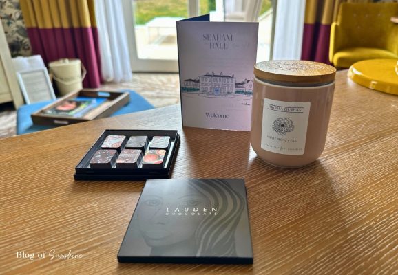 Welcome chocolates and an Aroma Durham candle on the desk in the Seaham Hall Garden Suite