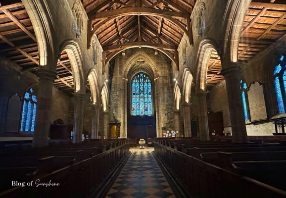 Central aisle and stained-glass window inside St John the Baptist Church Tideswell