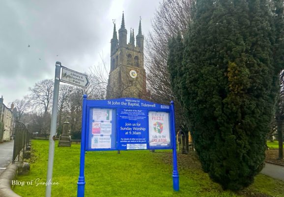 Welcome sign outside St John the Baptist Church Tideswell with tower in the background
