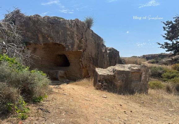 Small rock-cut tomb entrance at Tombs of the Kings in Paphos Cyprus surrounded by dry paths and limestone rocks