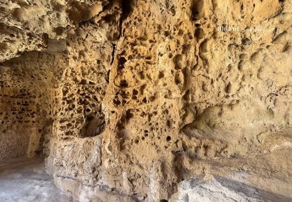 Weathered limestone walls inside Tombs of the Kings in Paphos Cyprus with natural pitted rock texture